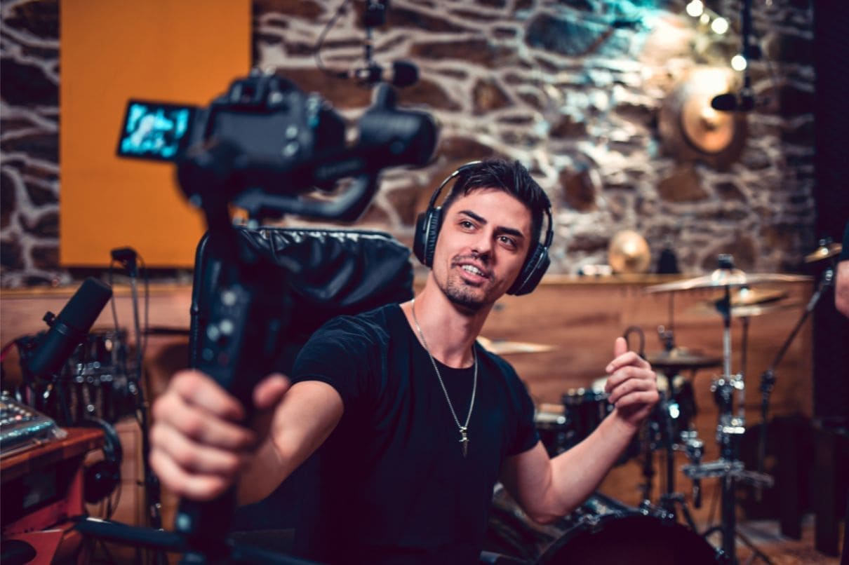 A man in a recording studio, holding a camera, capturing moments.